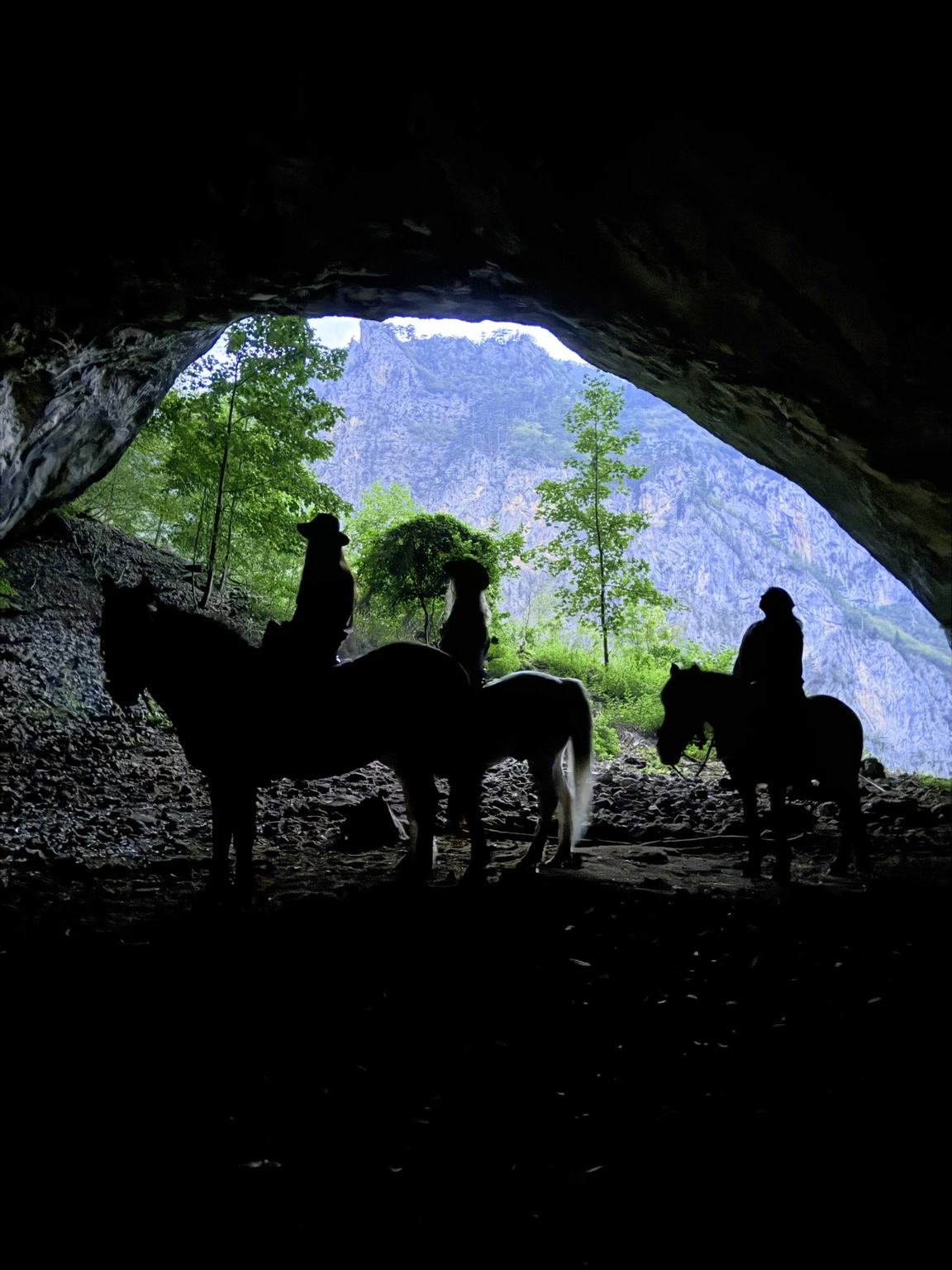 Horse riders silhouetted inside a cave