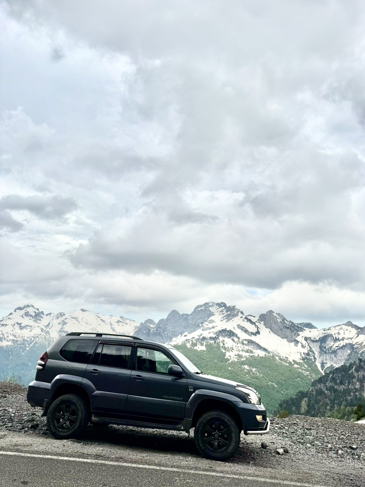 Jeep on a mountain road with snowy peaks